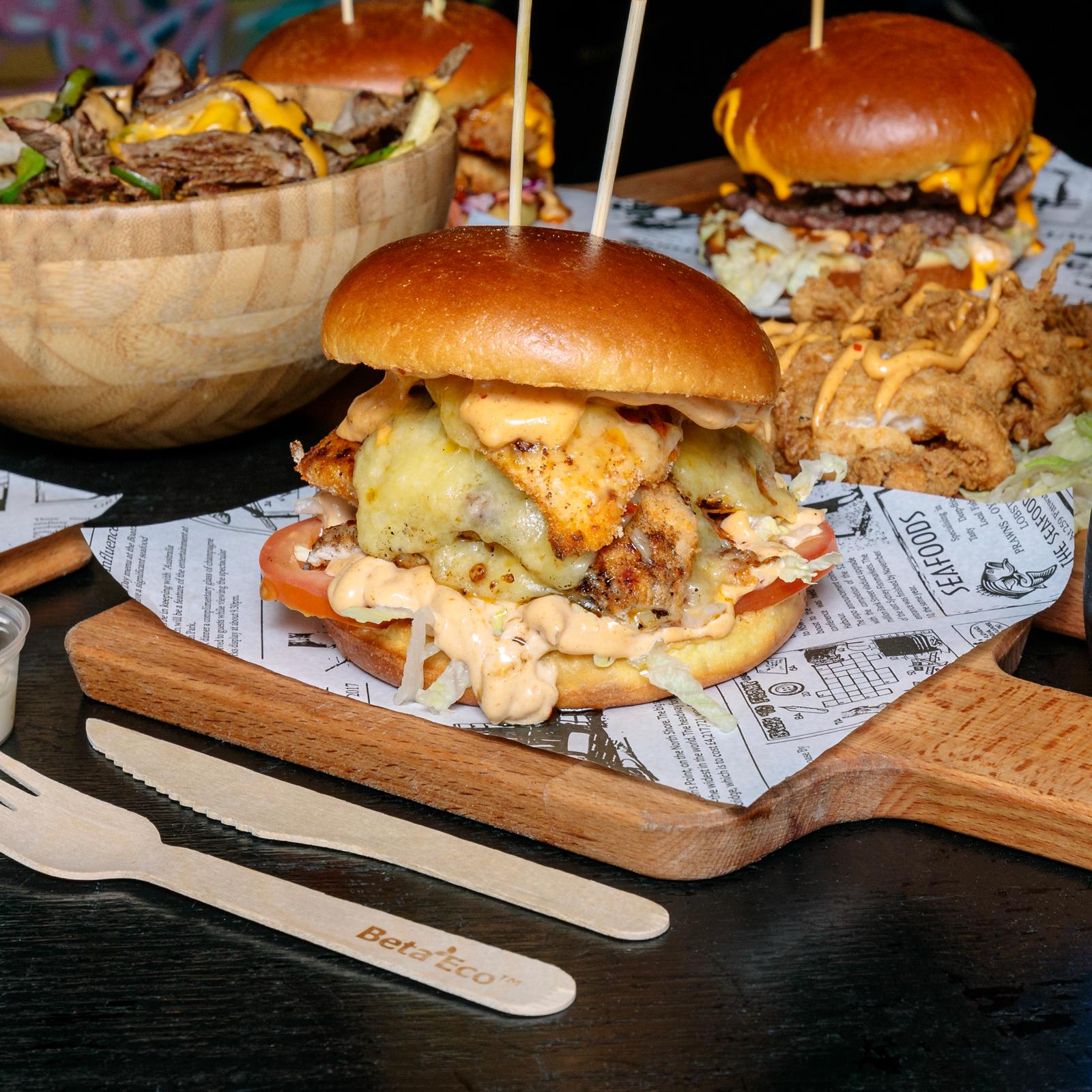 Crispy chicken burger with melted cheese on a wooden board